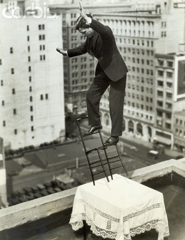 Man Balancing Of Chair On Bldg'S Roof