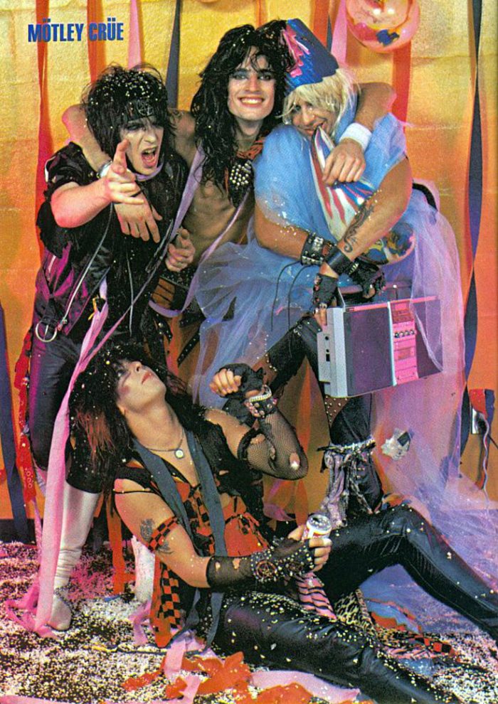 Nothing says hair metal more than wearing a pentagram headband while being hugged by a glitter-wielding, tutu-wearing fellow band member. 