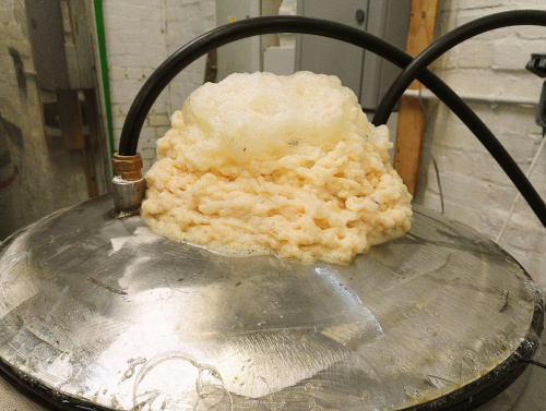 Barm foam collecting on the top of a modern brewing kettle.
